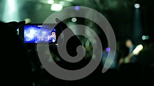 Hand silhouette recording video of live music concert with smartphone