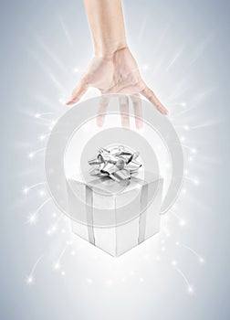 Hand with silver gift box and magic twinkles