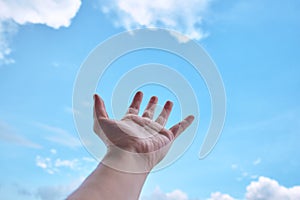 Hand with blue sky and cloud in background.