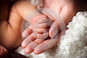 Hand of sleeping baby in the hand of mother