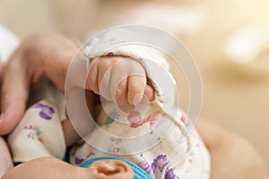 Hand of sleeping baby in the hand of mother while breastfeeding.