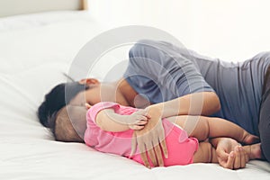 Hand of sleeping baby in the hand of mother close up on the bed. Mother with her baby sleeping on bed at home