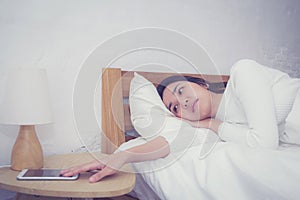 Hand of sleepy woman waking up with alarm clock on mobile phone.