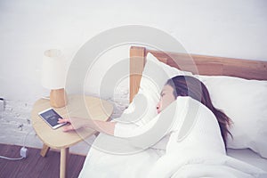 Hand of sleepy woman waking up with alarm clock on mobile phone.