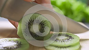 Hand slicing a kiwi with a knife