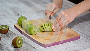 Hand slicing a kiwi with a knife, close up