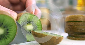 Hand slicing a kiwi with a knife, close up