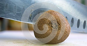 Hand slicing a kiwi with a knife, close up