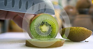 Hand slicing a kiwi with a knife, close uplose up