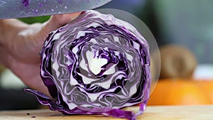 Hand slicing a purple cabbage with a knife