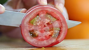 Hand slicing a red tomato with a knife