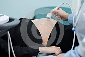 Hand slides transducer over abdomen checking signs of foetus