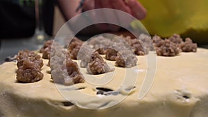 The hand slowly lowers the meat ball onto the dough prepared for sculpting.