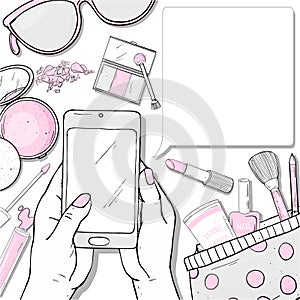 Hand with a smartphone and items of women`s cosmetics. Decorative cosmetics for face and nails. For beauty, fashion