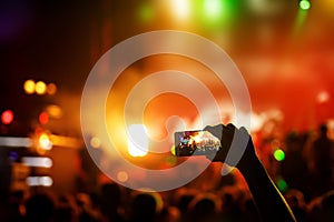 Hand with a smartphone records live music festival, live concert, show on stage