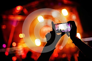 Hand with a smartphone records live music festival, live concert, show on stage