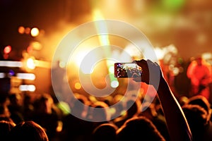 Hand with a smartphone records live music festival, live concert, show on stage