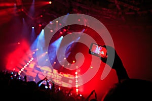 Hand with a smartphone records live music festival, Taking photo of concert stage