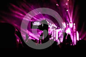 Hand with a smartphone records live music festival, Taking photo of concert stage