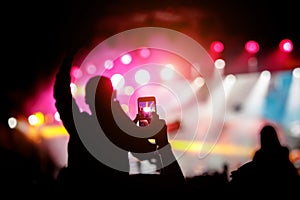 Hand with a smartphone shooting live music festival, concert