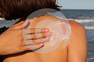 Hand smearing sun protection cream in girl's back