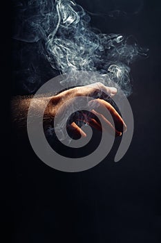 Hand in smoke on black background.