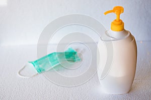 Hand soap bottle and surgical mask on white surface. General personal protective equipment for use in virus diseases outbreak or