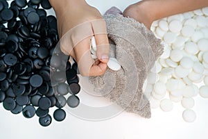 Hand with soft cloth  cleaning baduk or weiqi stones on white background