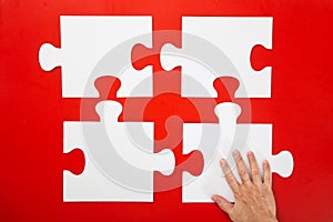 Hand solving a puzzle piece on red background