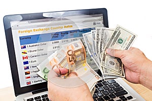 Hand sorting USD and EURO in front of currency exchange chart on