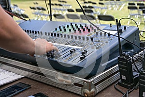 Hand of the sound mixer pushes buttons on a mixing console during soundcheck for an open air festival, selected focus, narrow