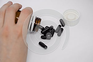 A hand spilling pills out of pill bottle