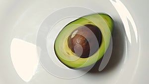 Hand spining avocado on the white plate. slow motion