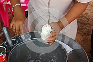 The hand is spinning milk ice cream in a bucket.