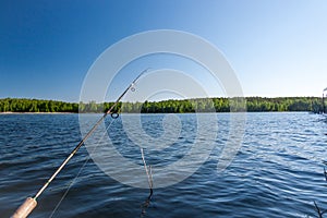 Hand with spinning and reel on the summer lake