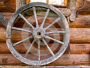 Hand spinning wheel on wall of old log house in the Russian village.