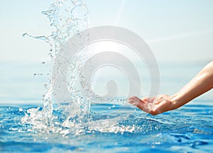 Hand splashing clean water in sun rays