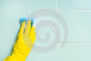 Hand with sponge, washing bathroom's wall