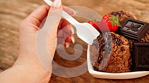 Hand with a spoon. Homemade chocolate ice cream with chocolate and strawberries