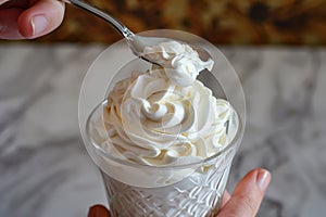 hand with spoon taking a dollop of whipped cream