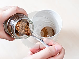 Hand spooning up second portion of instant coffee