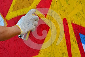 A hand with a spray can that draws a new graffiti on the wall