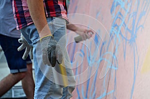 A hand with a spray can that draws a new graffiti on the wall