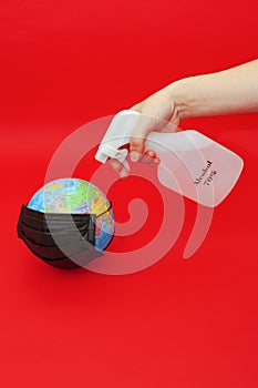 Hand spraying 70% alcohol on Earth globe model.