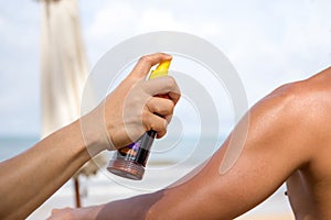 Hand spraying sunscreen protection on man shoulder