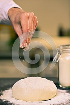 Hand sprinkle flour dough in kitchen