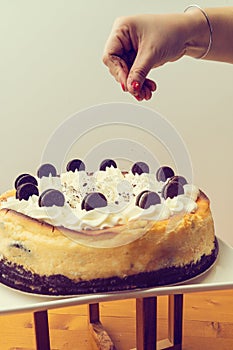 Hand sprinkling back biscuit on a cake