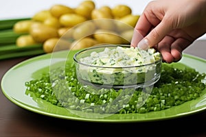 hand sprouting chives over a serving platter of potato salad