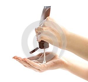 The hand squeezes the cream out of the tube onto the hand