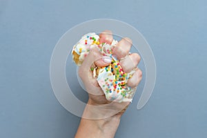 Hand squeezes the doughnut. One donut with white icing. An overhead view of a doughnut with colored sprinkles. Female